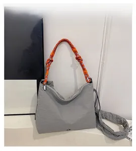 Detail view of dark grey nylon shoulder bag with pleated texture and colorful braided strap