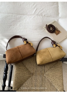 Macro shot of faux suede Boston bags with distinctive gold chain links and strap details