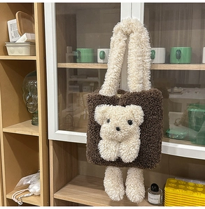 Detailed view of fluffy brown teddy bear plush tote bag hanging on a wooden cabinet handle
