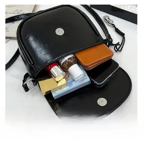 Detail view of the black saddle bag interior showing storage for phone and cosmetics