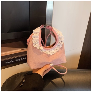 Detail of pink faux suede handbag with white lace trim and round metal handles