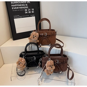 Detailed view of leopard-textured crossbody bags in brown and black with plush dog charms