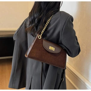 Detailansicht der dunkelbraunen Wildleder-Schultertasche mit goldener Kette am Modell