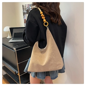 Detail of beige shoulder bag featuring unique strap with wooden beads and rings