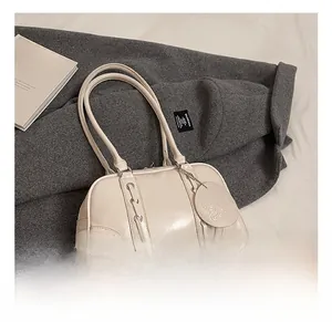 Detail shot of beige soft leather tote bag featuring eyelet lacing and metal brand charm
