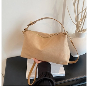 Detailed view of camel suede handbag with gold zipper and adjustable shoulder strap