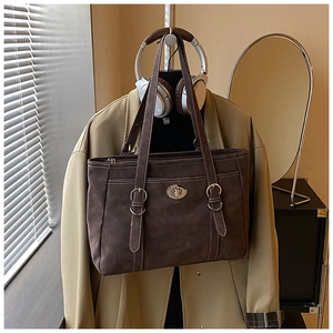 Detail of dark brown matte leather tote bag featuring white contrast stitching and metal lock