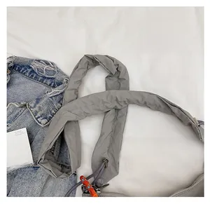 Detail of grey nylon crossbody bag showing the wide comfortable shoulder strap design