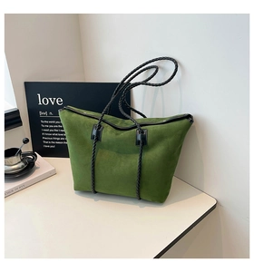 Detailed macro of green suede tote bag with black woven handles and minimalist stitching