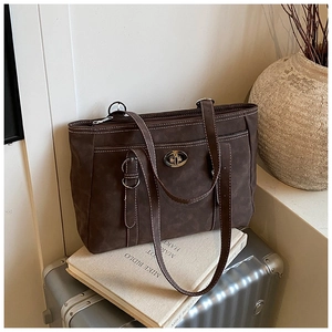Close-up of brown suede tote bag with white contrast stitching and silver metal buckle