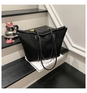Detail of black suede tote bag with braided rope handle and silver rivet accents