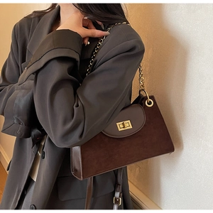 Detail of vintage matte brown shoulder bag with gold chain strap on a grey blazer model