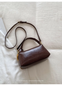Detailed macro view of dark brown retro Boston bag featuring glossy faux leather texture