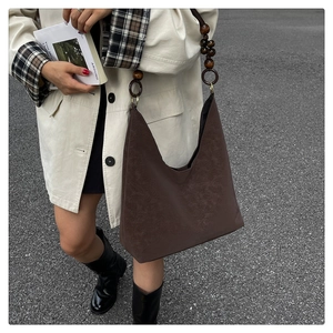 Detail of dark brown suede tote with unique round wooden bead strap and metal rings
