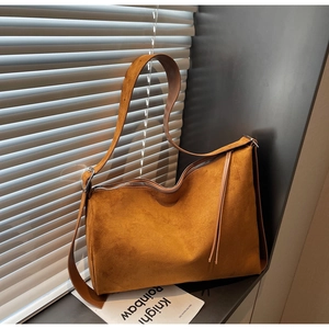 Close-up of vintage brown suede tote bag with zipper detail on a windowsill