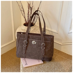 Detail of a dark brown tote bag with white contrast stitching and silver metal swivel clasp