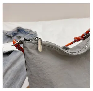 Detailed shot of a smooth silver zipper and colorful woven handle on a grey canvas bag