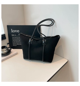 Detailed view of black tote bag featuring woven shoulder straps and premium matte finish