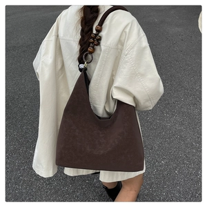Détail d'un sac hobo marron foncé avec ornements de perles en bois sur la bandoulière