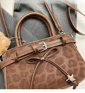 Detail of leopard print faux suede bag with star charm and plush pom-pom decoration