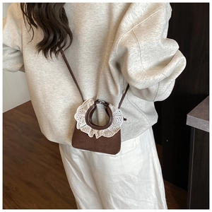 Detail of brown mini crossbody bag featuring white lace trim and matte finish texture