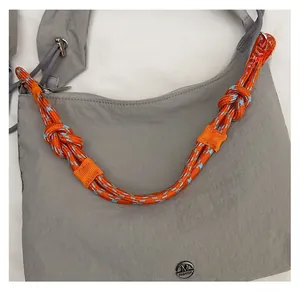 Close-up of gray nylon crossbody bag featuring a colorful rope handle and metal logo detail