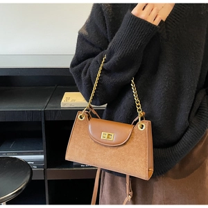 Detail of suede crossbody bag in caramel with gold chain and metal twist lock