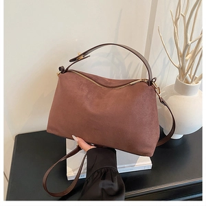 Close-up of chocolate brown suede tote bag with gold zipper and textured handle detail