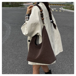 Detailed view of dark brown suede hobo bag featuring retro wooden beaded shoulder strap