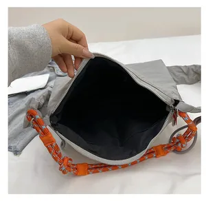 Detail view of the gray crossbody bag interior with trendy orange and blue braided rope strap