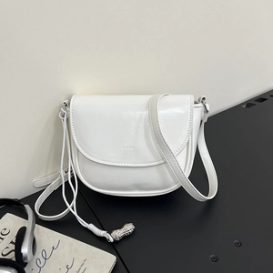 Detail of white saddle bag with woven drawstring and silver peanut metal pendant