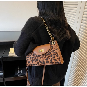 Detail der Tasche mit Leopardenmuster, goldenem Drehverschluss und klobiger Kette
