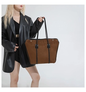 Close-up of caramel suede tote bag with black rope handles and leather piping detail