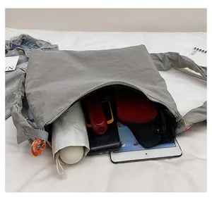Spacious gray nylon crossbody bag showing storage for tablet, umbrella and phone