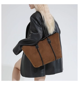 Close-up of brown suede hobo bag with woven strap detail and protective metal rivets