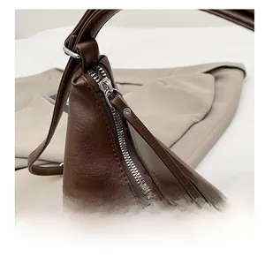 Close-up of smooth silver zipper and lychee pattern leather on dark brown shoulder bag
