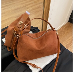Detail view of brown suede crossbody bag with light gold hardware and zip closure