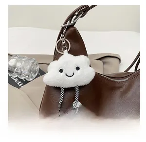 Detail of creative plush cloud pendant with striped legs on brown leather bag