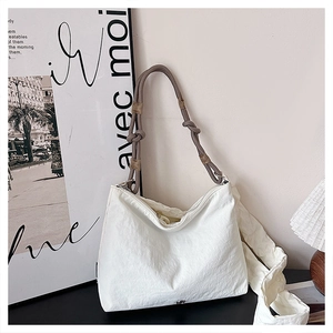 Detail of white casual dumpling bag with textured fabric and unique rope shoulder strap