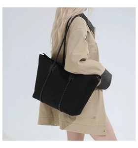Detail of a large black tote bag featuring unique double braided leather shoulder straps