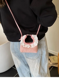 Mini pink crossbody bag with lace trim and slim strap shown on a female model