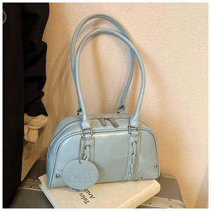 Detail of light blue mirror-finish patent leather tote bag on silver luggage