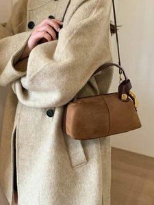 Brown suede Boston pillow bag with gold buckles worn with a beige cashmere coat