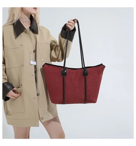 Close-up of a burgundy suede tote bag with black woven straps on a fashion model