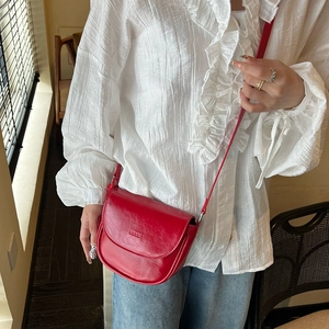 Close-up of red leather saddle bag with adjustable strap and embossed detail