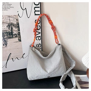 Close-up of grey fabric crossbody bag with vibrant blue and orange rope handle detail