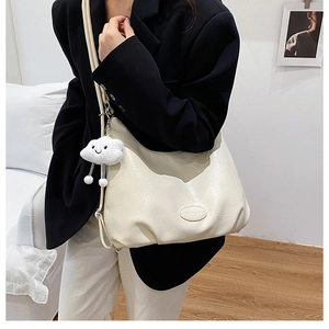 Detail view of the soft pleated texture and cloud charm on the cream-white tote bag