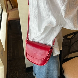 Detail of red leather saddle bag with LUUU embossed logo worn by a model