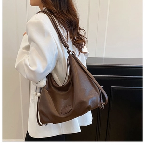 Detail shot of a dark brown soft leather tote bag with wide strap and fashion logo