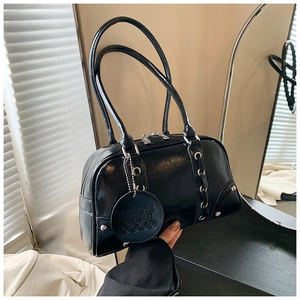 Detail of glossy black leather tote bag with silver rivets and sleek metallic accents